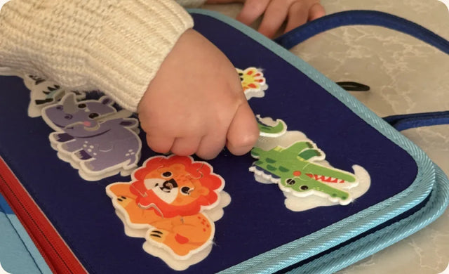 Small hands working the buckles and zipper on the Busy Board
